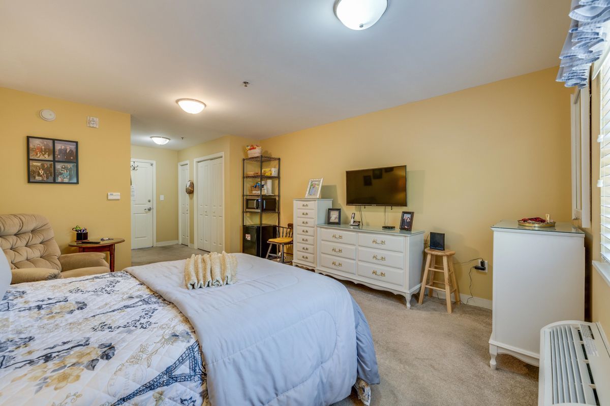 A bedroom with a bed , dresser , television and chair.