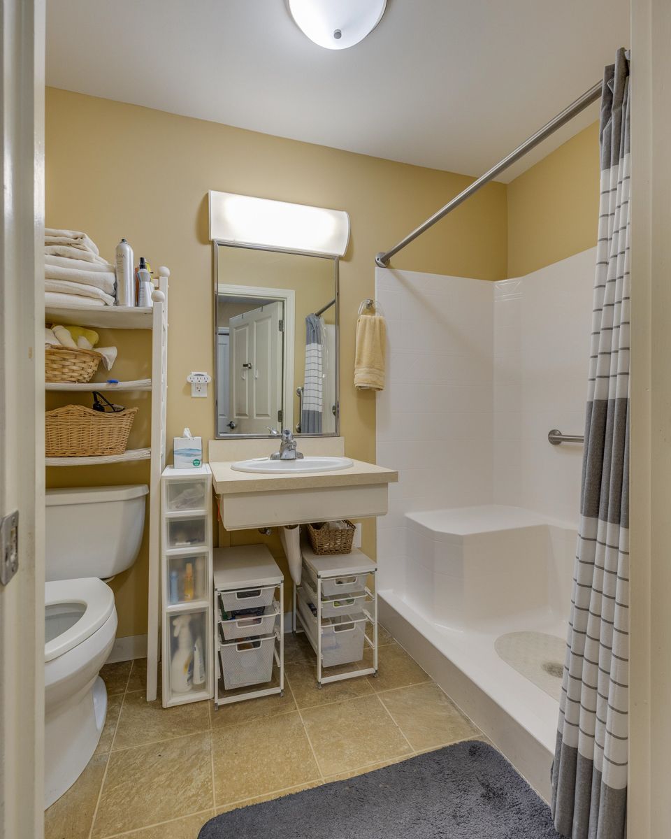 A bathroom with a toilet a sink and a shower