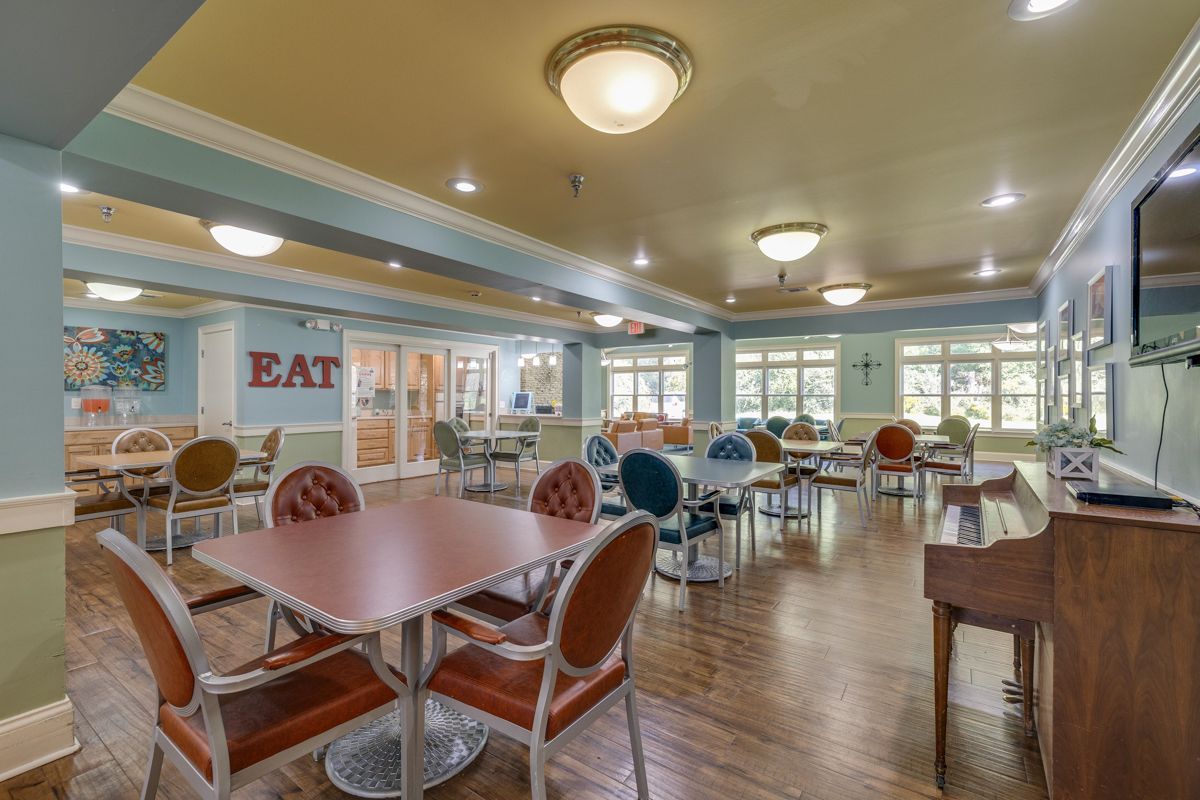 A large dining room with tables and chairs and a piano.