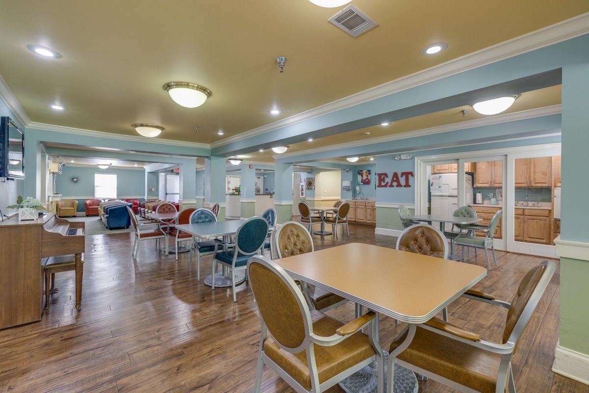 A large dining room with tables and chairs and a piano.