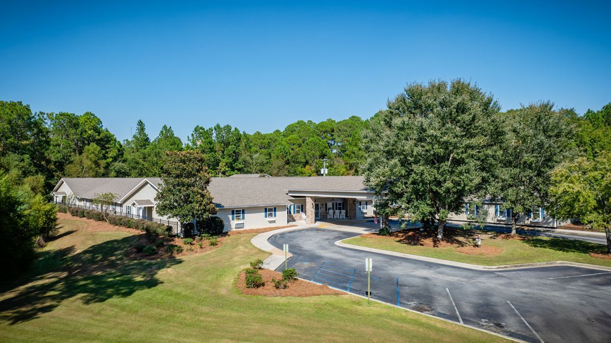 An aerial view of a house with a lot of trees in front of it.