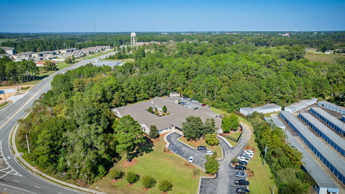 An aerial view of a building surrounded by trees and a parking lot.
