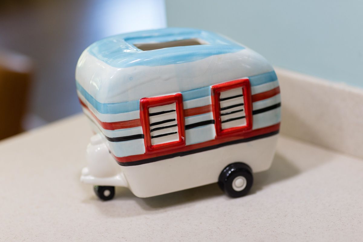 A ceramic tissue box in the shape of a camper van is sitting on a counter.