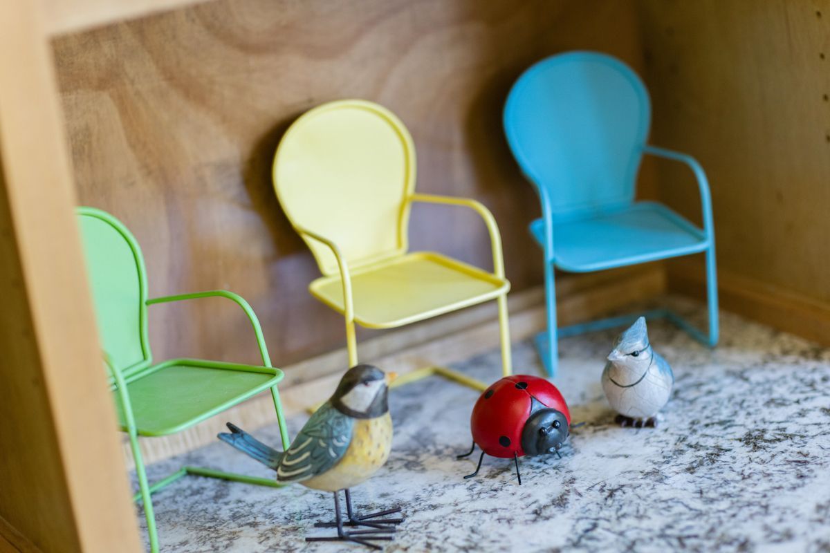 A ladybug is sitting next to a bird and a chair in a room.