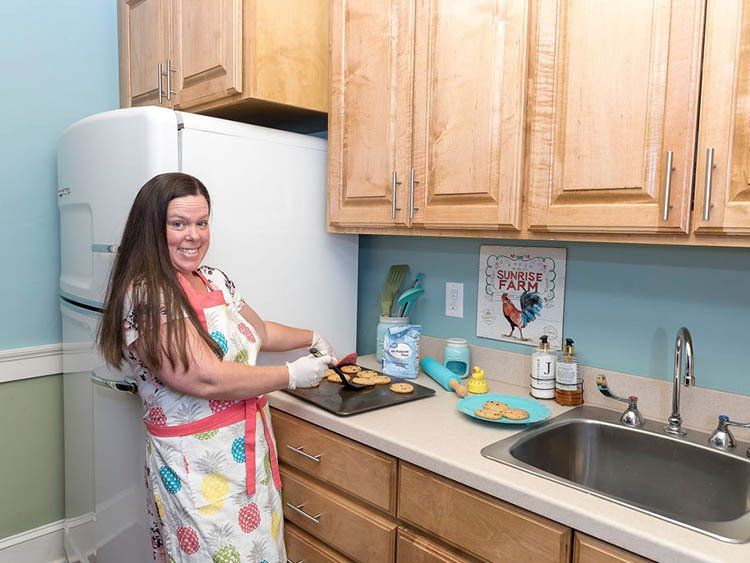 A woman is standing in a kitchen preparing food.