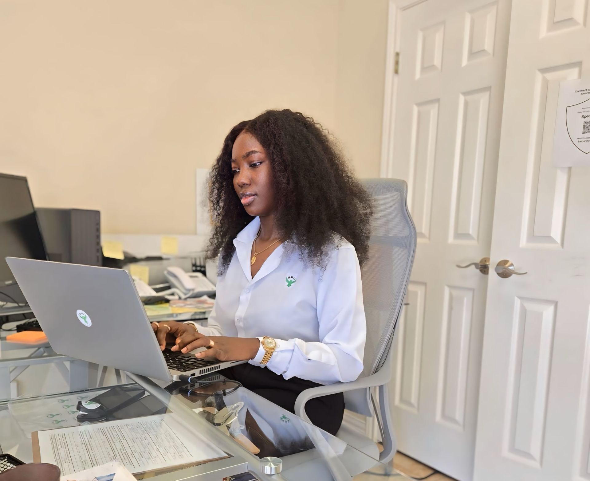 A woman is sitting at a desk using a laptop computer.