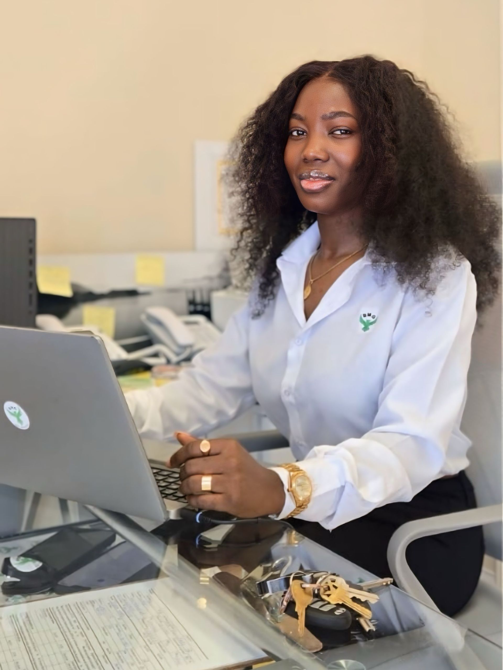 Christabel Teke is sitting at a desk in front of a laptop computer.