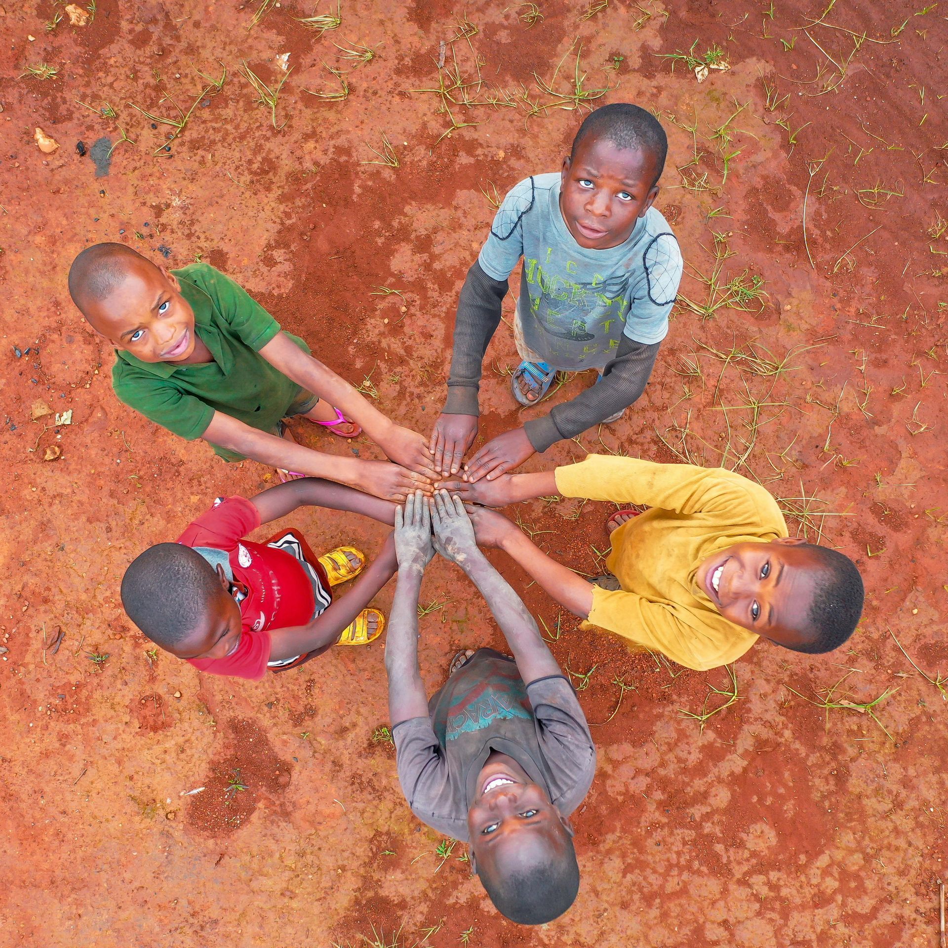 Five kids with their hands put together in a circle