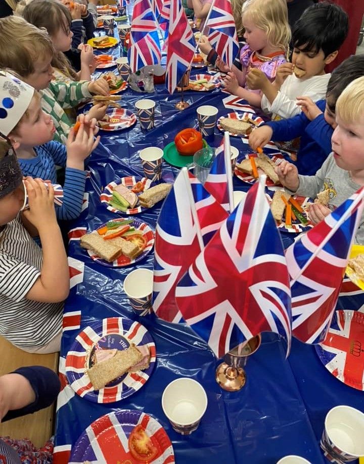 A group of children are sitting at a table with british flags on it.
