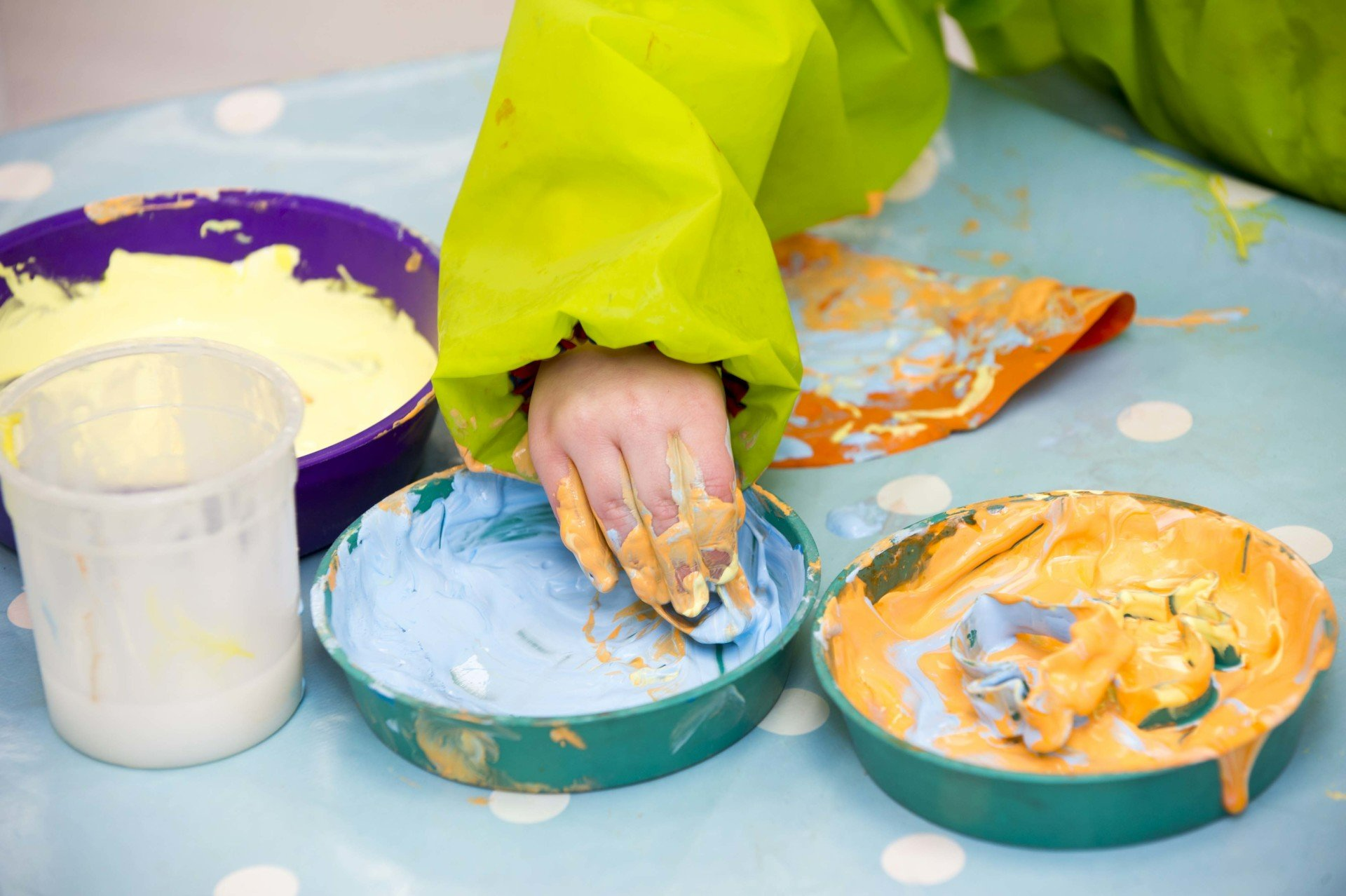 A child is playing with paint on a table.
