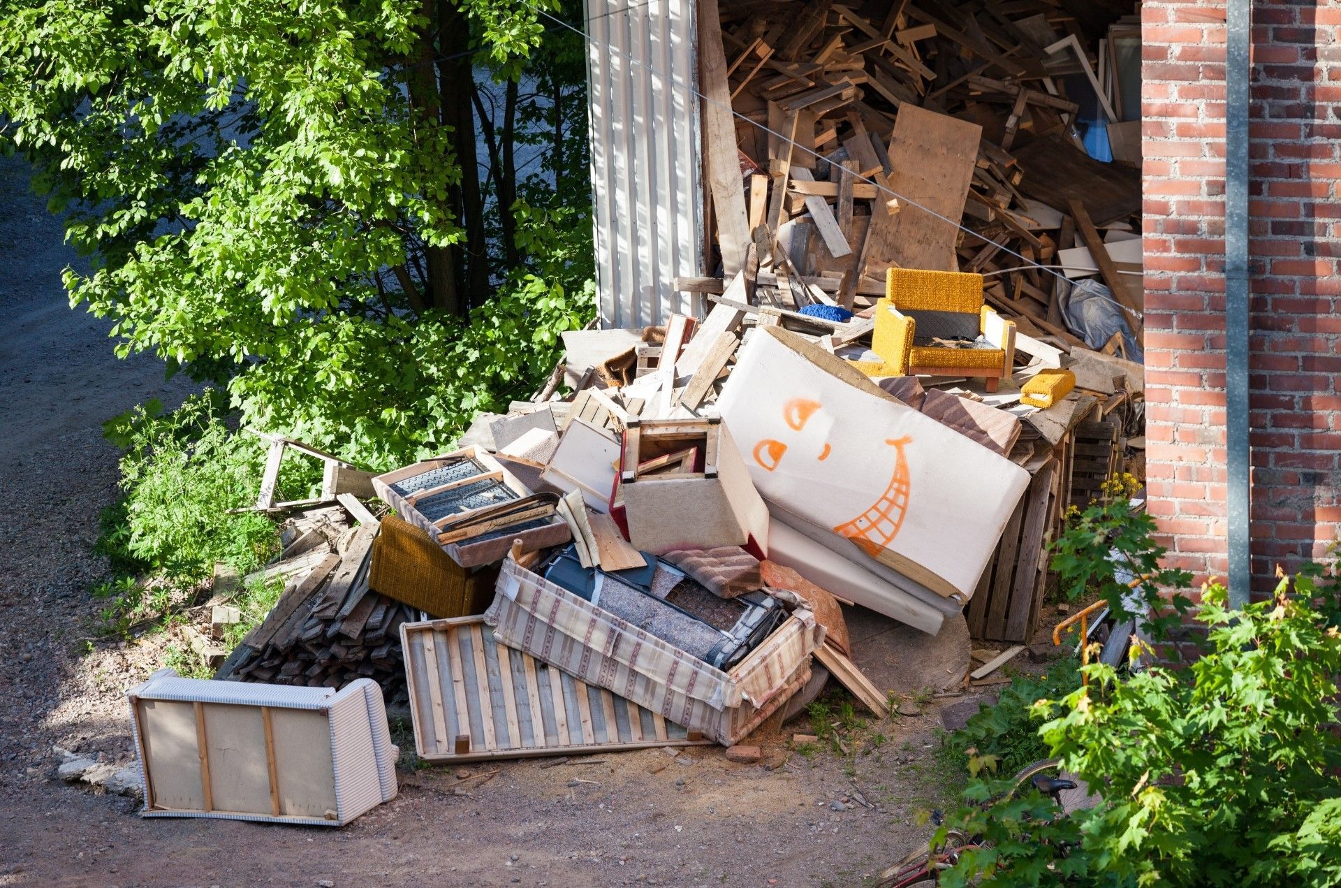 Mac's Junk Removal | A pile of junk is sitting in front of a brick building.