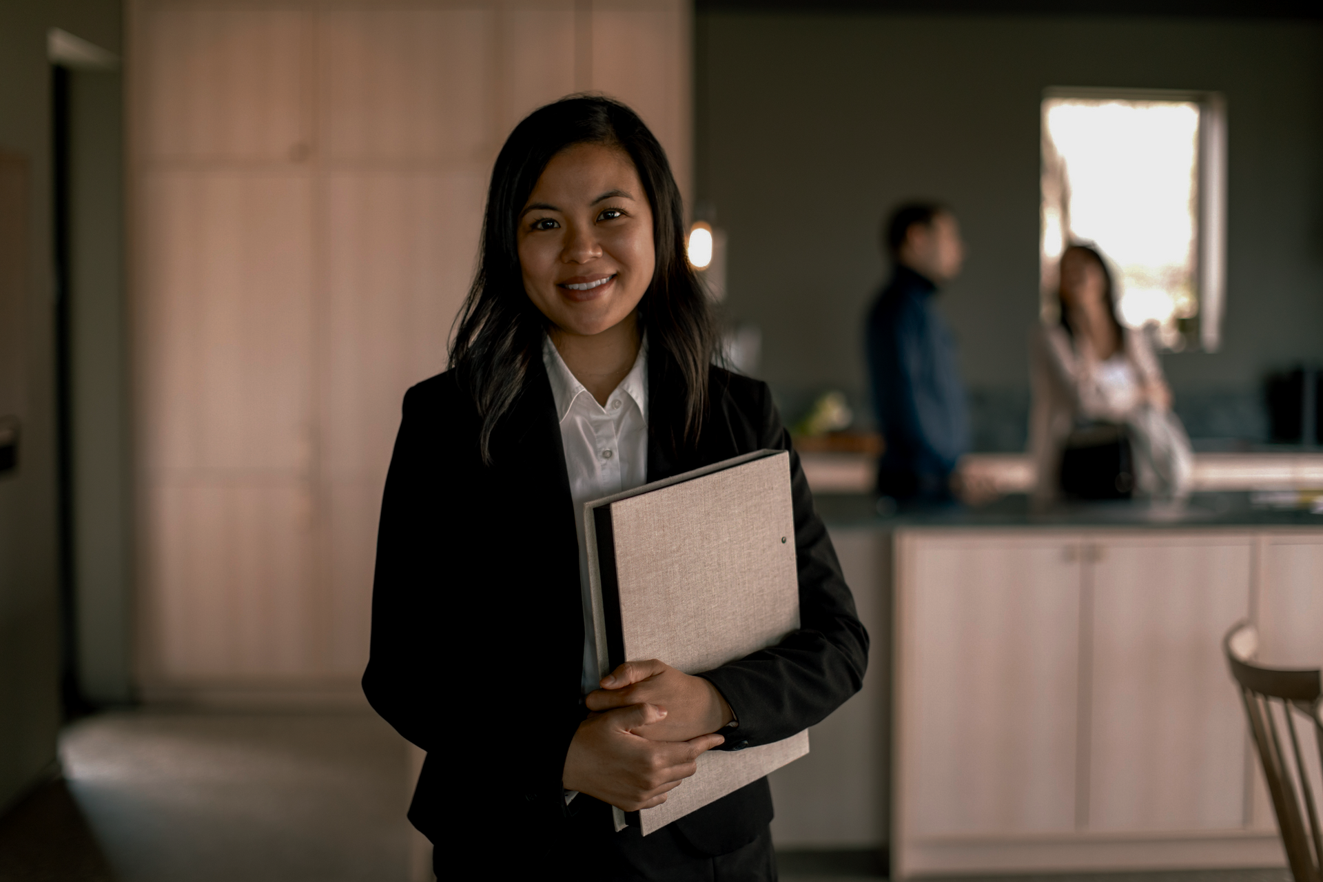 A Woman in A Suit Is Holding a Folder in A Kitchen | St. Augustine, FL | Superior Real Estate Services