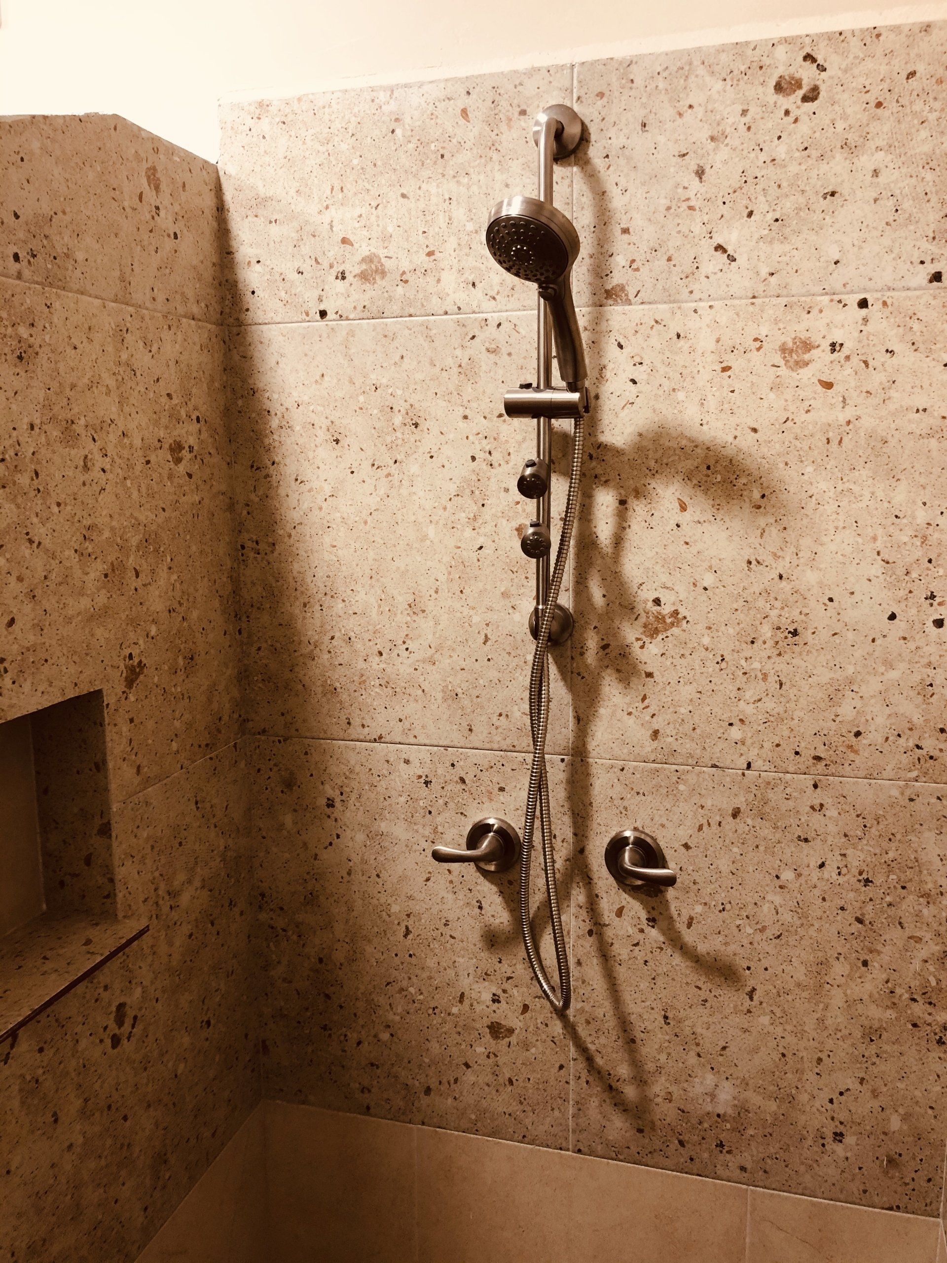 A shower head is hanging from a tiled wall in a bathroom.