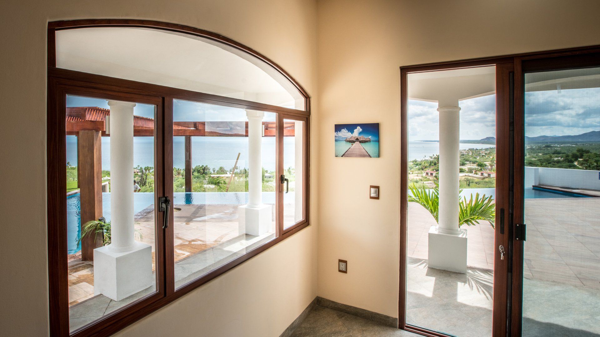 A room with a lot of windows and a sliding glass door leading to a balcony.