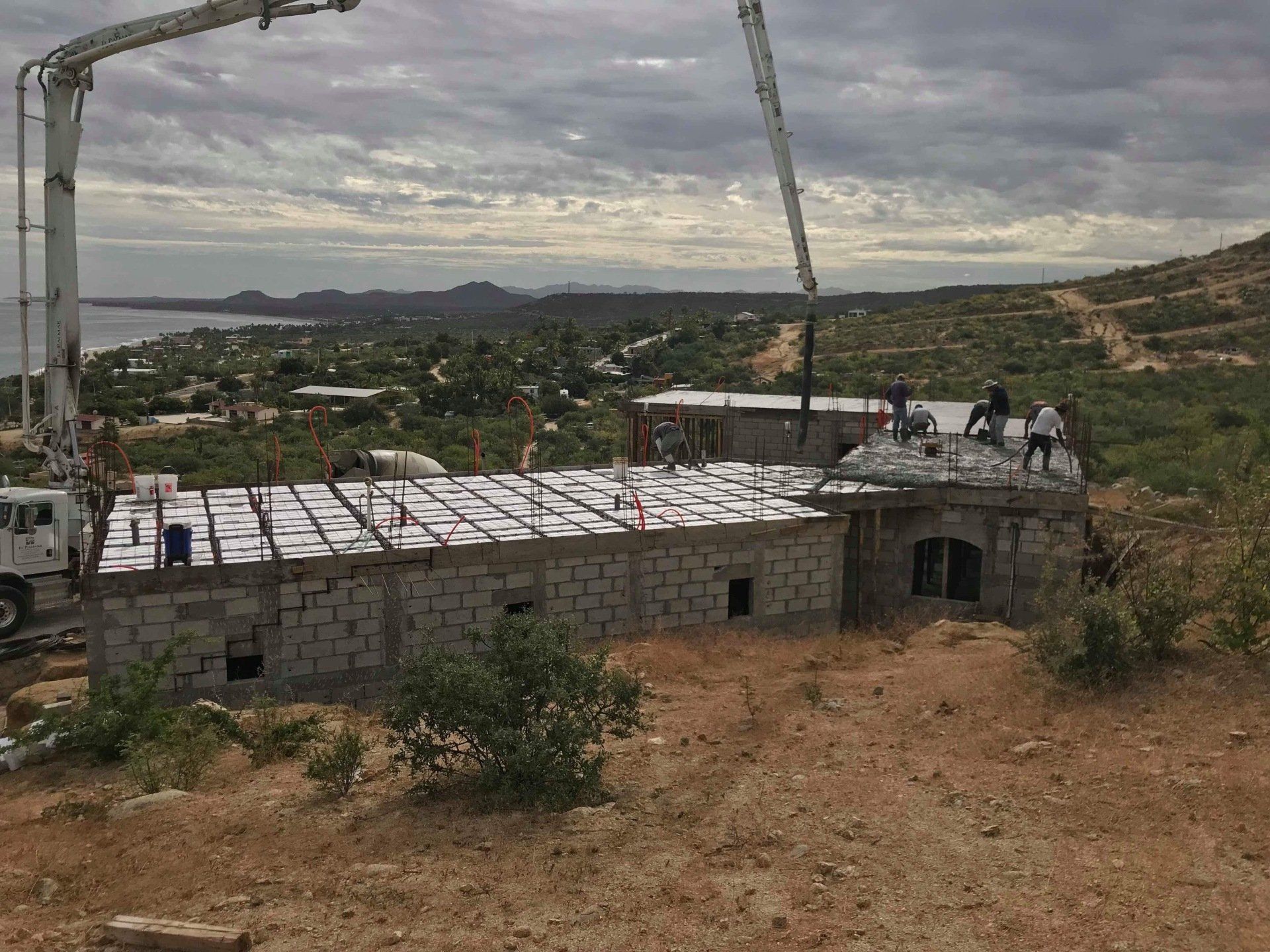 A crane is being used to pour concrete on top of a building.