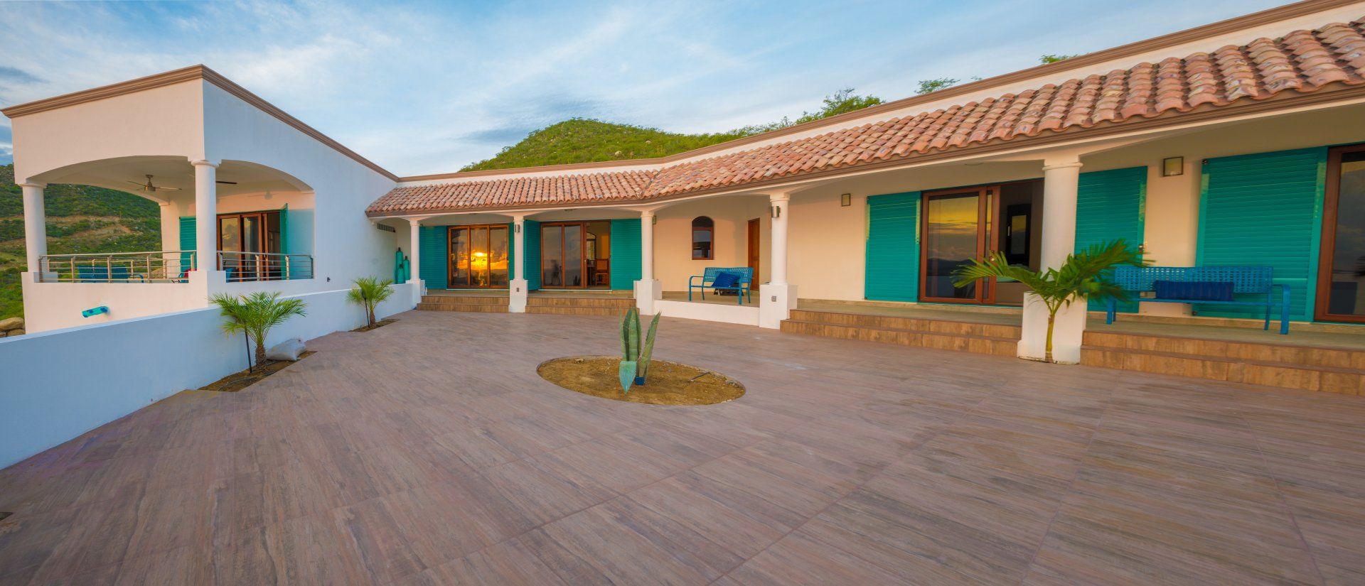 A large white house with blue shutters and a patio in front of it.