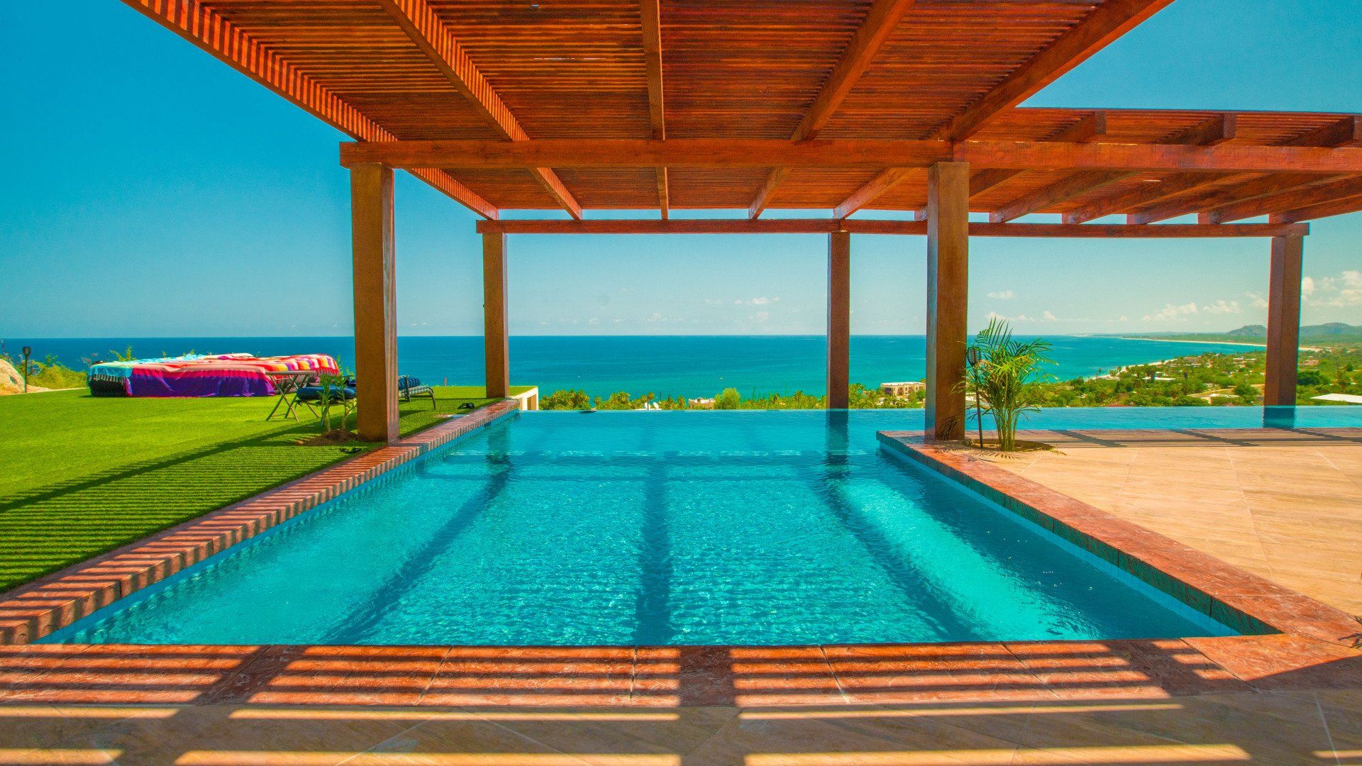 A large swimming pool with a pergola overlooking the ocean.