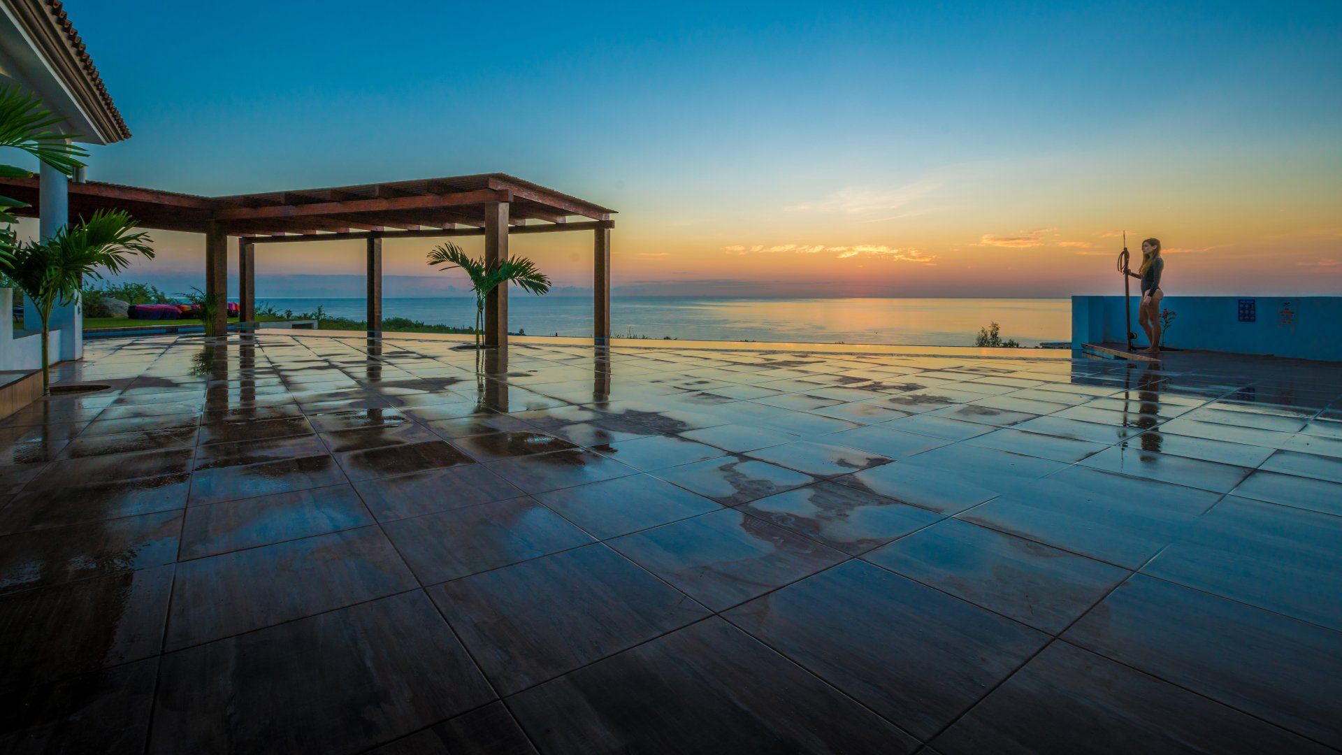 A swimming pool with a view of the ocean at sunset.