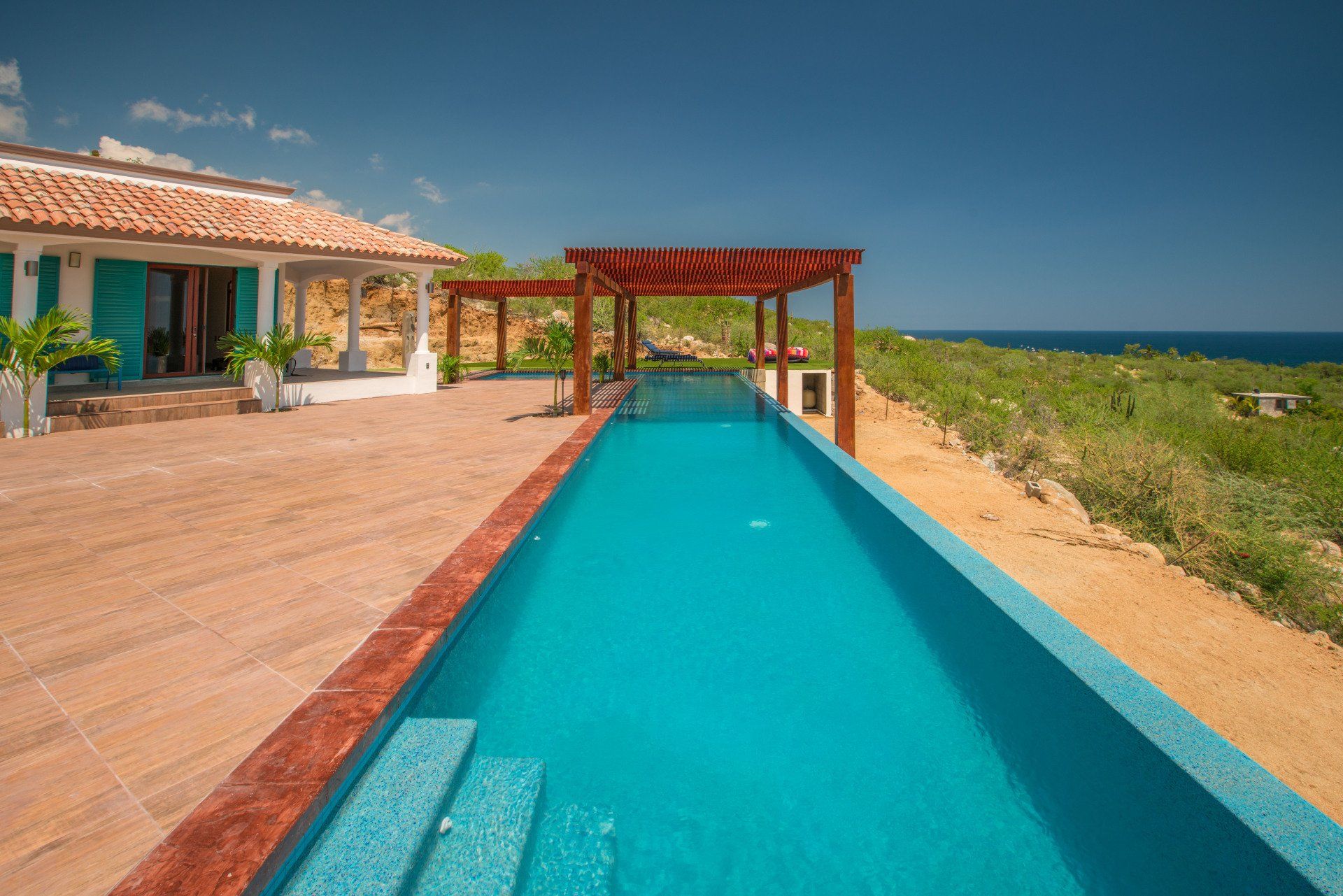 There is a large swimming pool in front of a house.