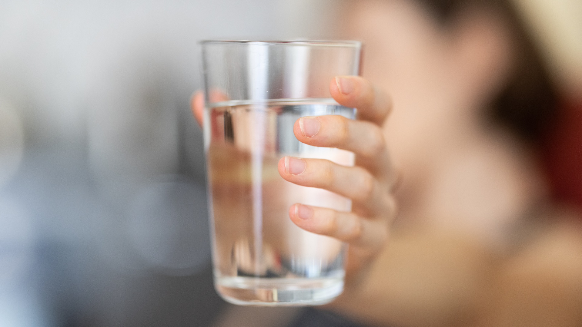 A woman is holding a glass of water in her hand.