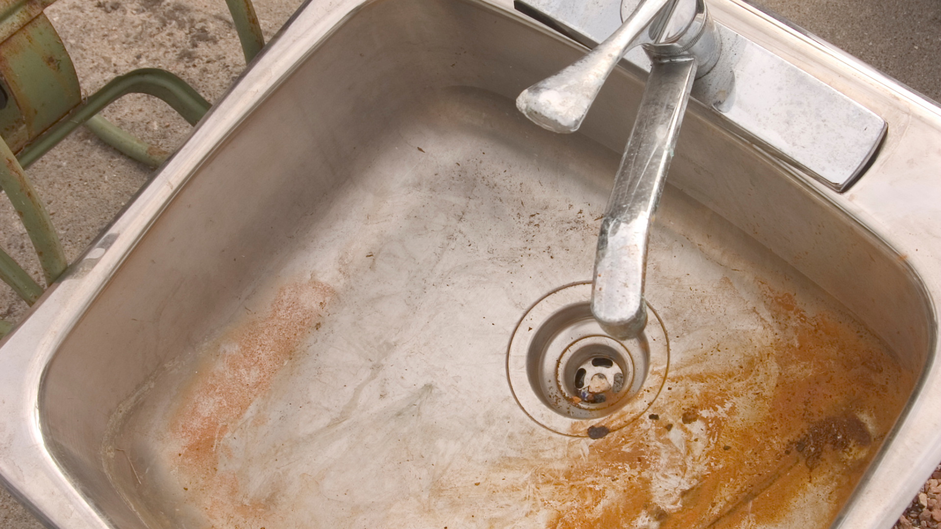 A dirty kitchen sink with a faucet in it