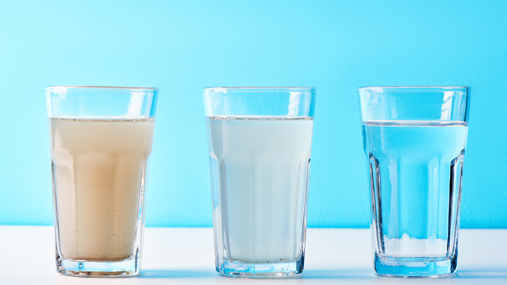 Three glasses of different types of water are lined up on a table.