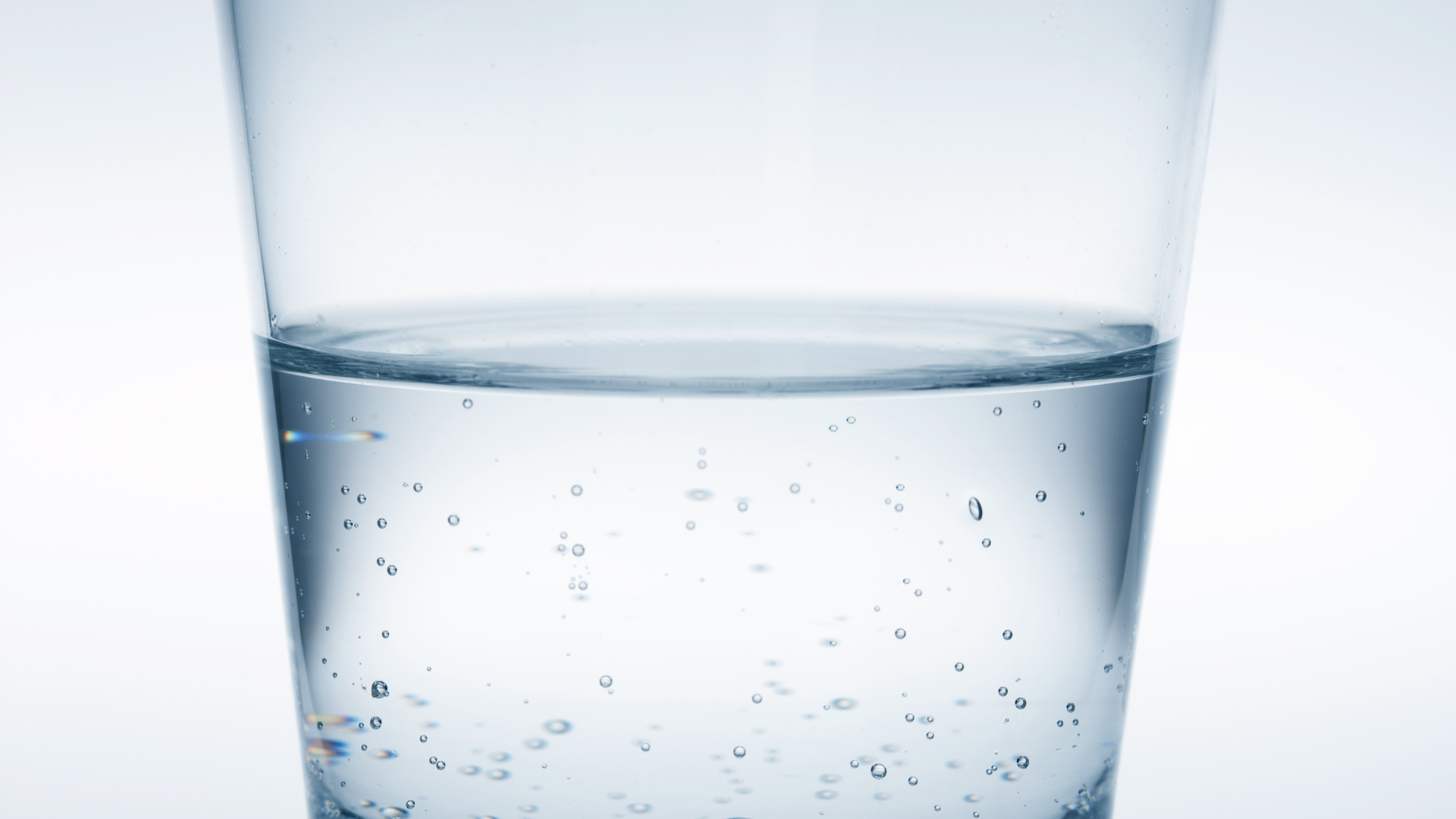 A glass of water with bubbles in it on a white background.