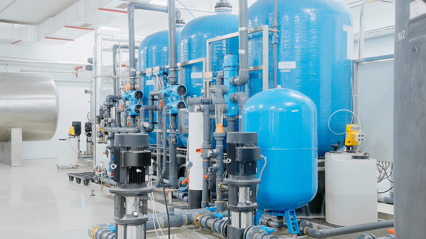 A large room filled with lots of blue tanks and pipes.