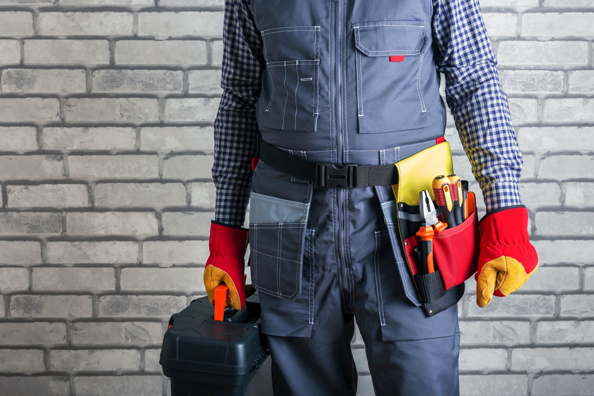 A man in overalls is holding a wrench over his shoulder.