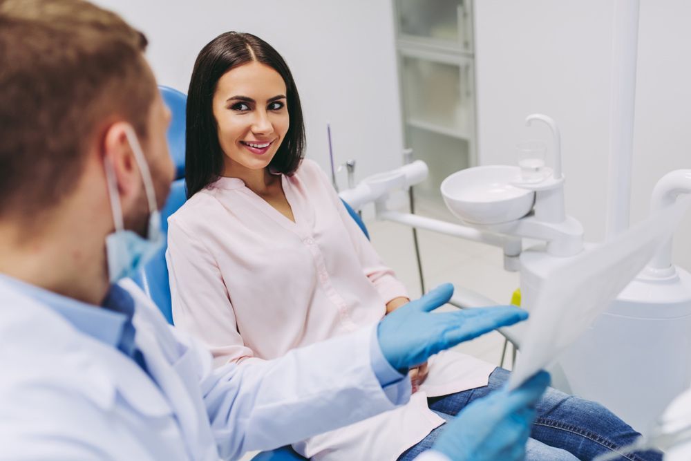 Woman Is Sitting In A Dental Chair Talking To A Dentist — Dentist On Tweed in Tweed Heads, NSW