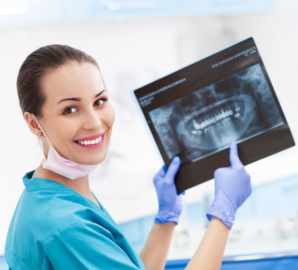 A Female Dentist Is Smiling While Holding An X-ray Of Her Teeth — Dentist On Tweed in Tweed Heads, NSW