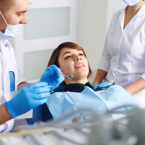 Woman Is Sitting In A Dental Chair While A Dentist Examines Her Teeth — Dentist On Tweed in Tweed Heads, NSW