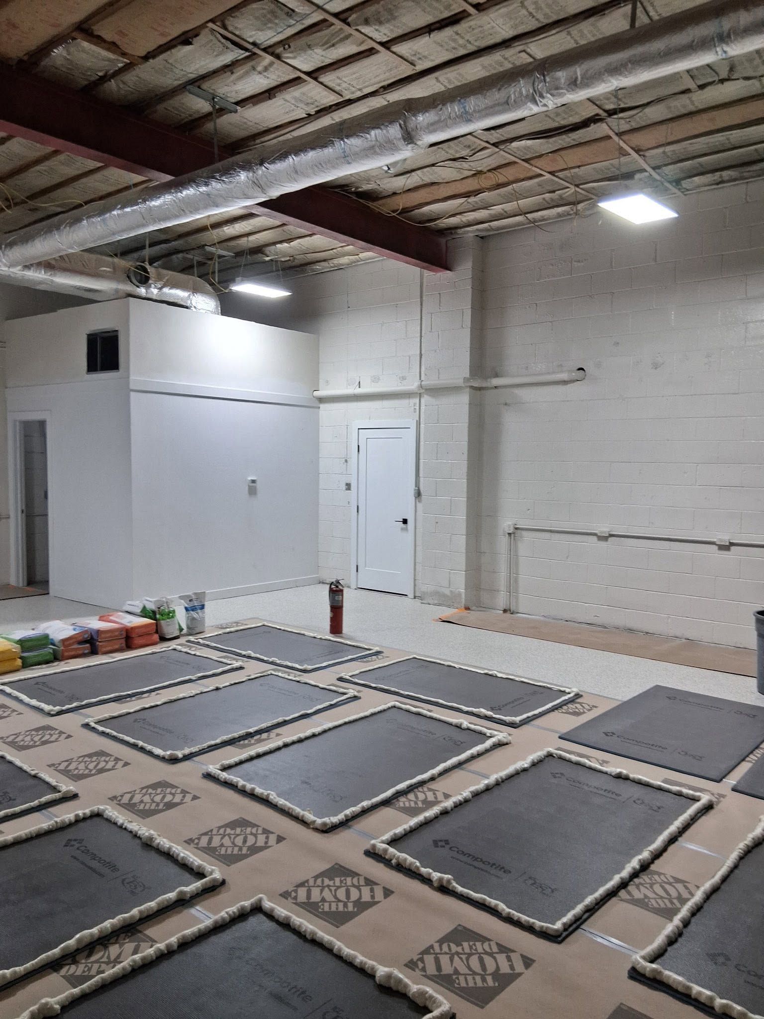 Empty white warehouse interior with high ceiling, polished floor, and large doorway at the far end