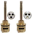 A pair of brass faucet cartridges with three holes in them.