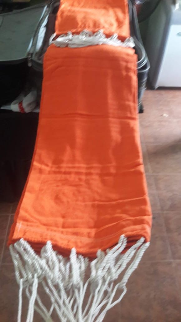 Hamaca naranja con flecos blancos.