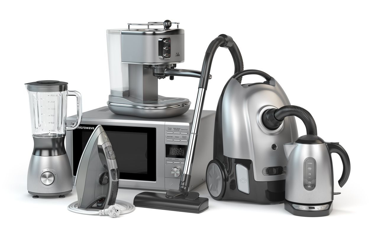 Surtido de electrodomésticos plateados sobre superficie blanca: licuadora, microondas, plancha, cafetera, aspiradora y hervidor de agua.
