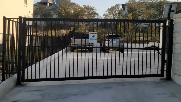 A white van is parked behind a black gate