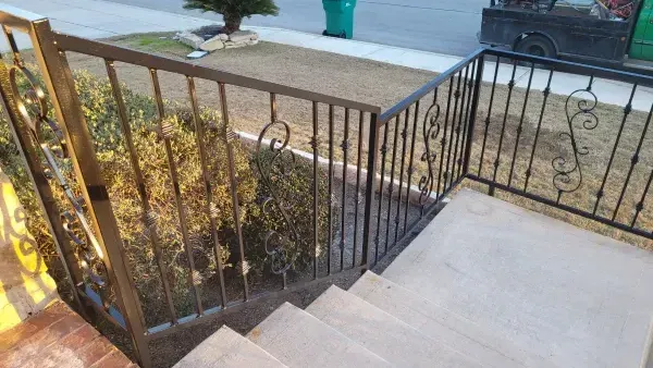 A staircase with a wrought iron railing and a truck in the background