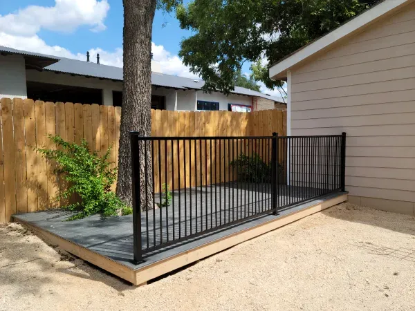 A wooden fence surrounds a deck in front of a house