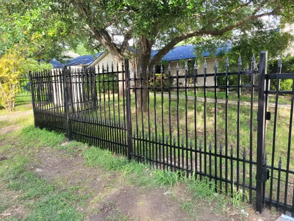 A black metal fence with a gate in front of a house.