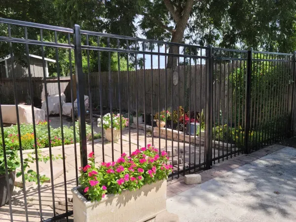 A fence with a planter of pink flowers behind it