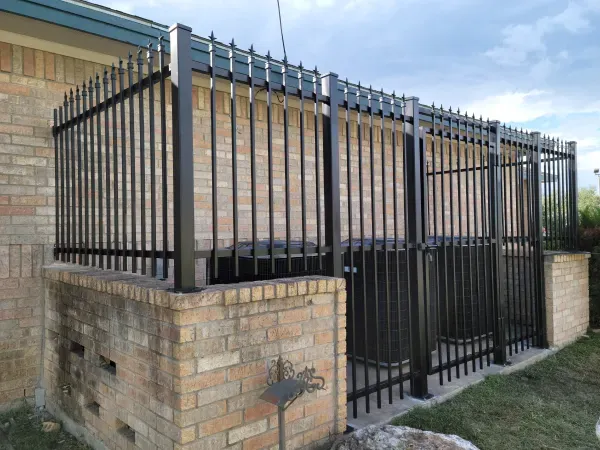 A black metal fence is surrounding a brick building.