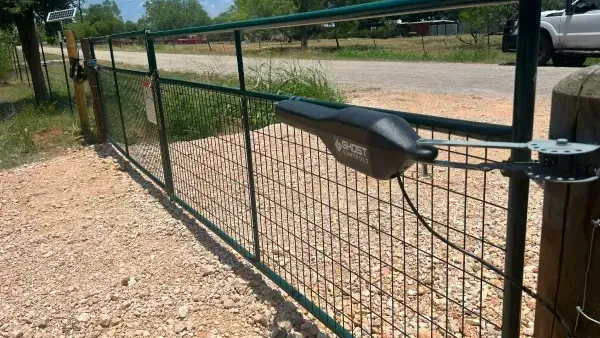 A gate with a motor attached to it is sitting on a gravel road.