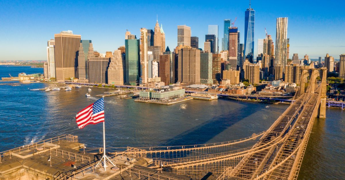 New York City skyline with the Brooklyn Bridge and American flag — representing Vibe 35 New York, a fast, effective 35-minute workout experience that transforms body and mind.