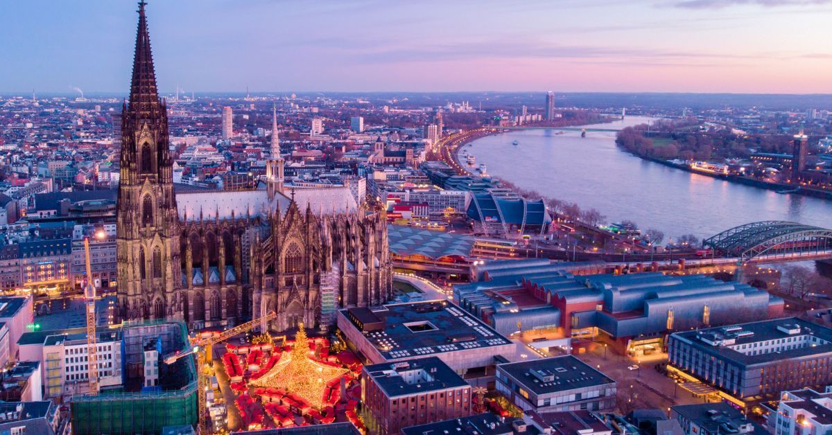 Aerial view of Cologne Cathedral and Christmas market near the Rhine River during sunset in Germany
