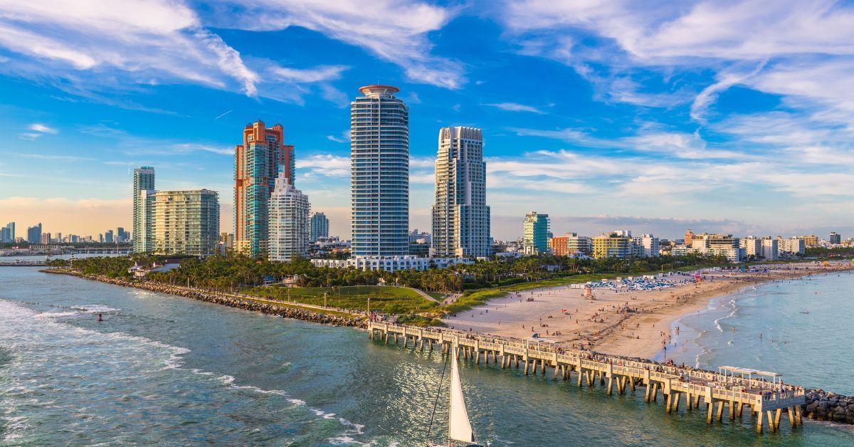 Scenic view of a Florida beach with a vibrant skyline, showing clear skies, high-rise buildings, and people enjoying the coast
