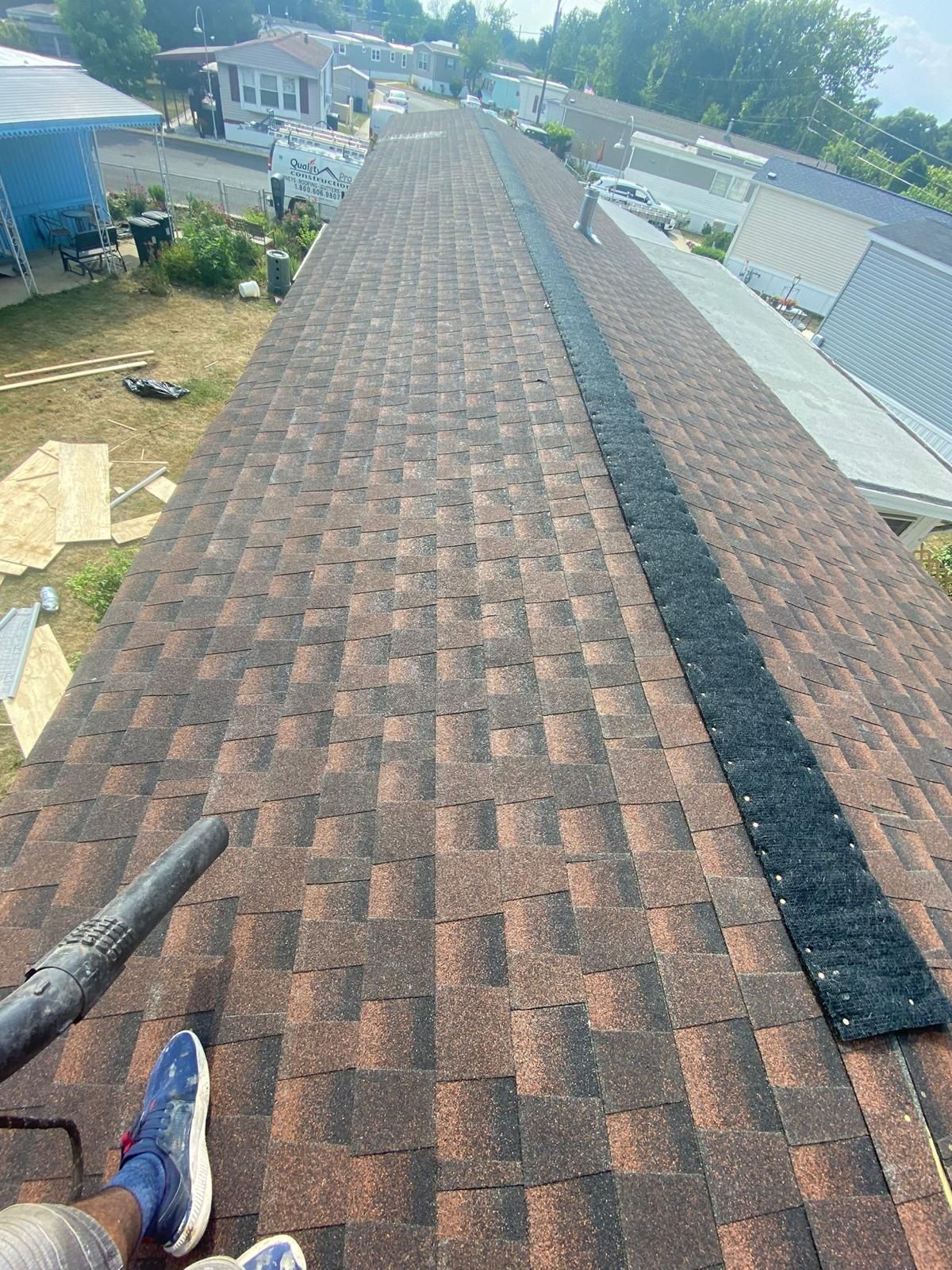A person is sitting on top of a roof with a blower.