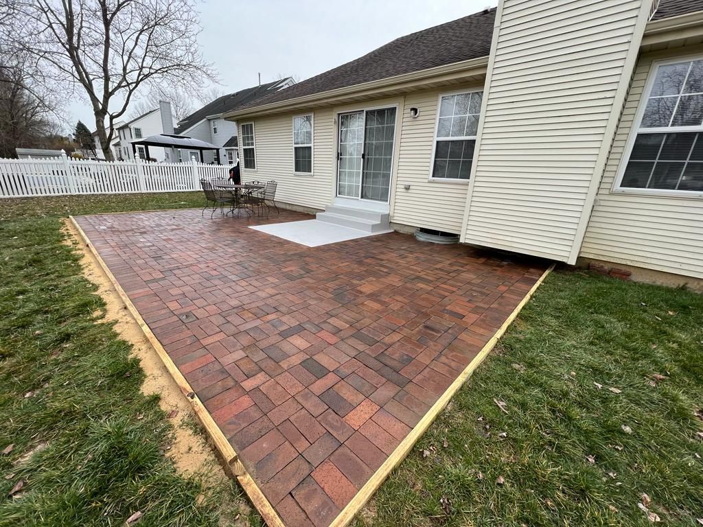A brick patio is being built in front of a house.