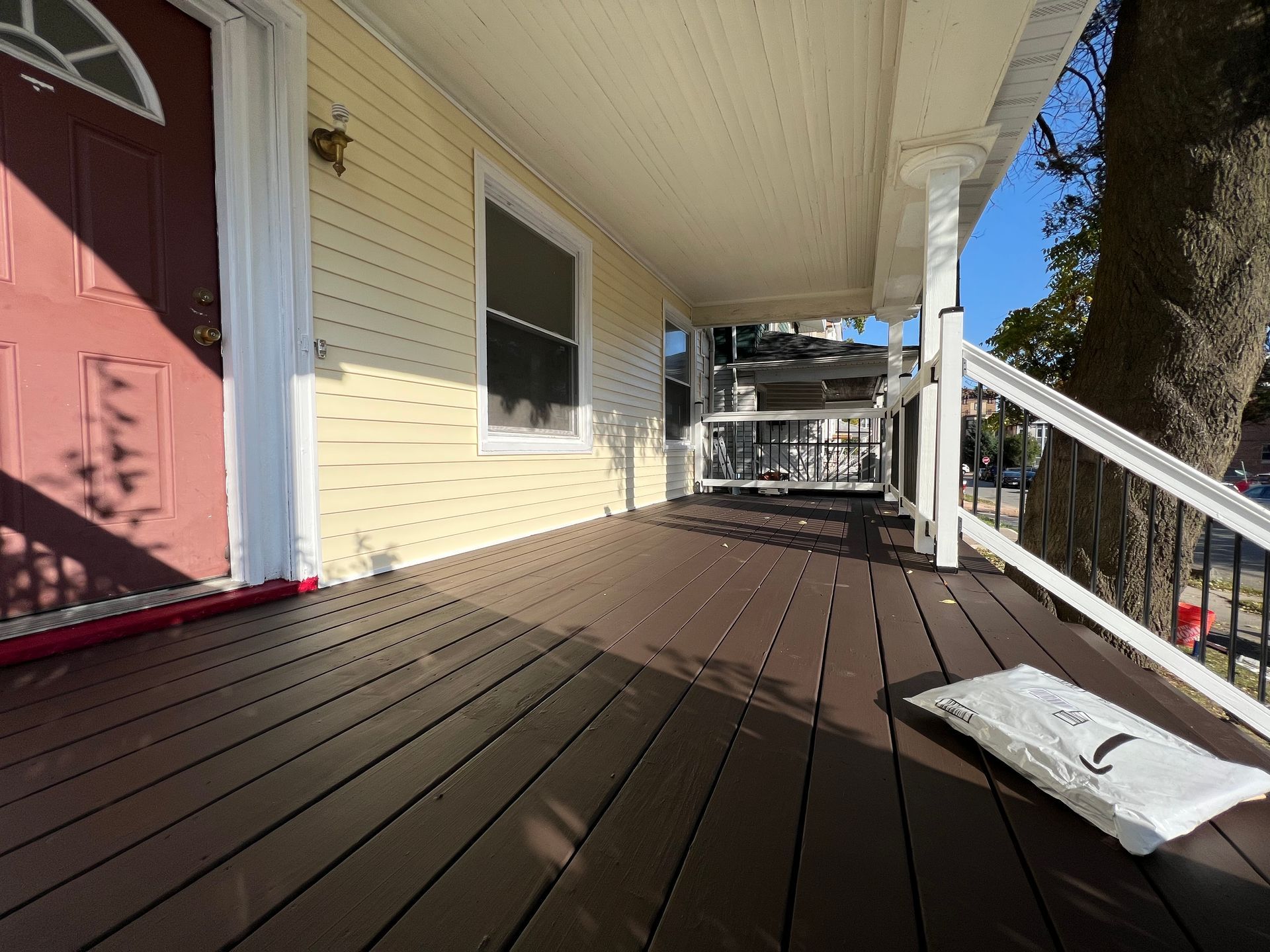 A porch with a red door and a white railing