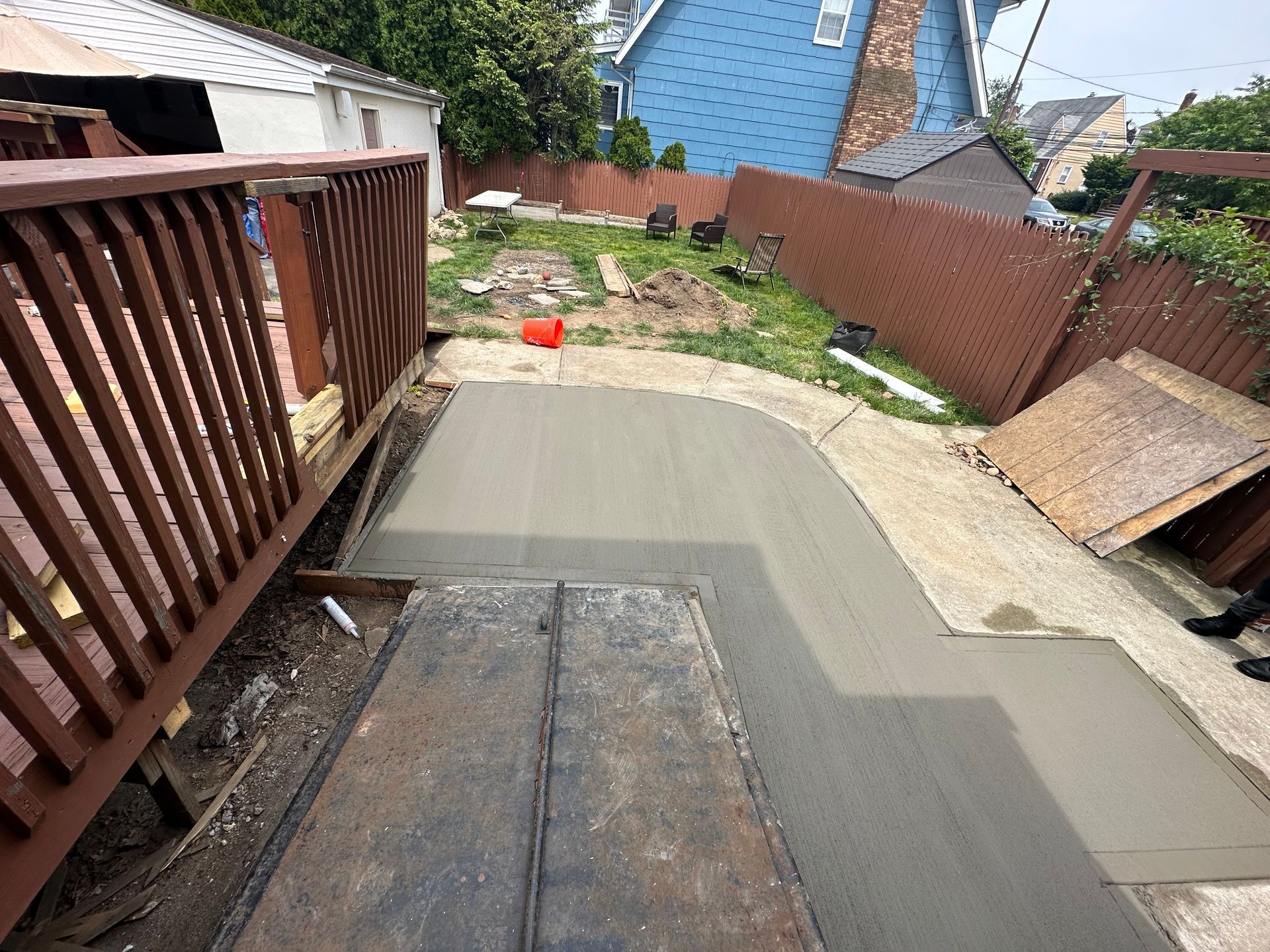 A concrete walkway is being built in the backyard of a house.